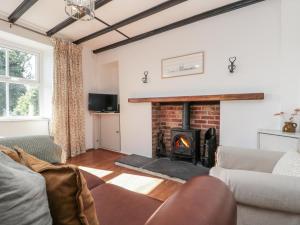 un salon avec une cheminée et un canapé dans l'établissement Honeysuckle Cottage, à Oswaldkirk