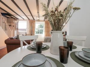 une salle à manger avec une table blanche et un vase avec des fleurs dans l'établissement Honeysuckle Cottage, à Oswaldkirk