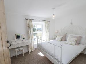 une chambre blanche avec un lit et une fenêtre dans l'établissement Honeysuckle Cottage, à Oswaldkirk
