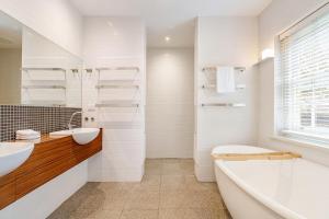 a white bathroom with a tub and a sink and a bath tub at Charming Red Brick Estate in Kew 5BR & Playhouse in Melbourne +30 photos