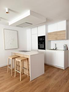 a kitchen with white cabinets and a table and stools at Megara Home in Soria