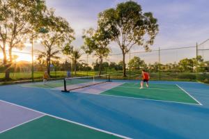 two people playing tennis on a tennis court at Cuc Phuong Mineral Retreat in Ninh Binh