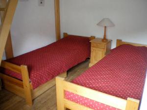 two twin beds in a room with a lamp on a table at Aigles 19 Bajeux Bât 2 in La Clusaz