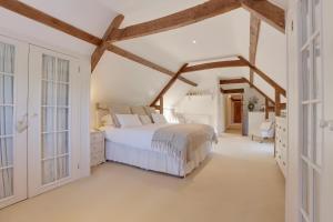 a bedroom with a white bed and wooden beams at Lake Cottage in Swindon