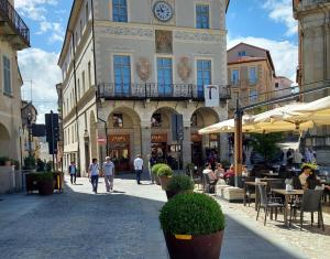 Un grupo de personas caminando por una calle con un edificio con un reloj. en Dimora Vico, en Mondovì