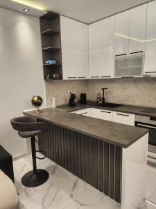a kitchen with white cabinets and a bar with a stool at Stan na dan Zvezdara in Belgrade