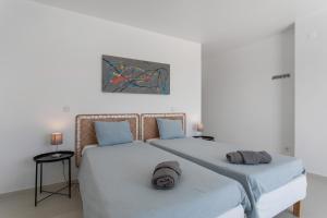 twee eenpersoonsbedden in een witte kamer met een schilderij aan de muur bij Peace House Lourinhã in São Bartolomeu +37 foto's