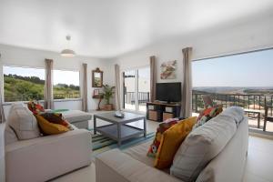 een woonkamer met witte meubels en grote ramen bij Peace House Lourinhã in São Bartolomeu