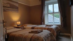 two beds in a room with a window at The Golden Lion Hotel in Horton in Ribblesdale