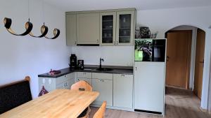 a kitchen with white cabinets and a wooden table at Ferienhof Reiter in Waging am See