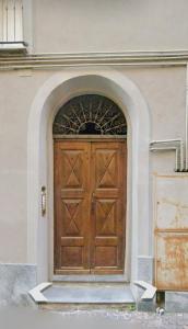 una gran puerta de madera en un edificio blanco en Dimora Vico, en Mondovì