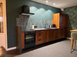 a kitchen with wooden cabinets and a black stove at De Crullsweijde in Kloosterhaar