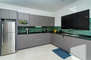 Una cocina con gabinetes blancos y un refrigerador de acero inoxidable. en Mon Plaisir Residence, en Paramaribo