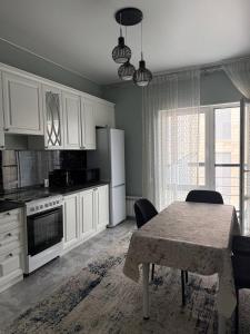a kitchen with white cabinets and a table with chairs at Tamerlan Residence in Shymkent