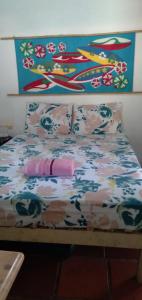 a bed with a flowered sheet and pillows on it at Quarto duplo de frente para o mar, Casa da Jô in Angra dos Reis