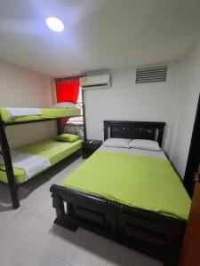 a bedroom with two bunk beds and green sheets at Patuca Balcon in Rodadero