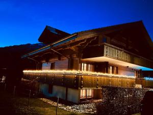 a building with lights on the side of it at night at Alpine Haven Chalet II in Iseltwald