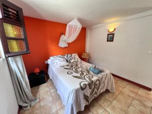 a bedroom with a bed and an orange wall at Cosy T2 dans village de pêcheurs, plage à pied in Sainte-Luce