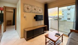 a living room with a couch and a tv and a table at Apartamento T1 Pau da Bandeira in Caliços