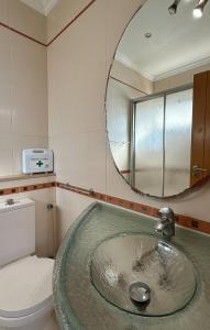 a bathroom with a sink with a mirror and a toilet at Apartamento T1 Pau da Bandeira in Caliços