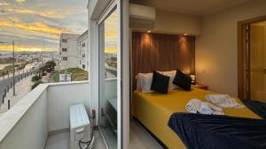 a bedroom with a yellow bed and a balcony at Apartamento T1 Pau da Bandeira in Caliços