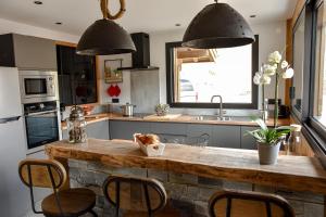 a kitchen with a counter with chairs and a sink at Le Chalet Margaux La Bresse in La Bresse