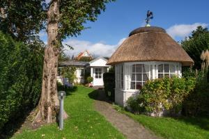 a gazebo with a thatched roof in a yard at Haus Hideaway in Westerland (Sylt)