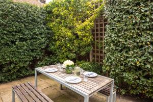 a wooden table with plates and flowers and two chairs at The Brewer's House in Southwold