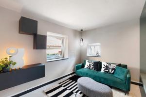 a living room with a green couch and a chair at Torri e tramonti in Albenga