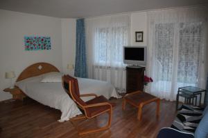 ein Schlafzimmer mit einem Bett und einem Stuhl und einem Fernseher in der Unterkunft 1 12 Zi Wohnung mit persönlichem Charme - b48574 in Vulpera