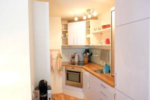 eine kleine Küche mit weißen Schränken und einer Spüle in der Unterkunft 1 12 Zi Wohnung mit persönlichem Charme - b48574 in Vulpera + 17 Fotos