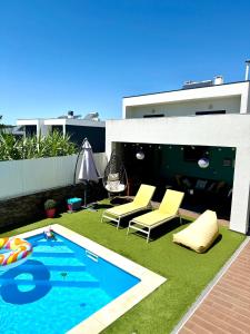 a backyard with a swimming pool and chairs and a house at Valadares House in Corroios