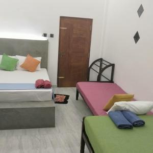 a room with two beds with colorful sheets and a door at Rooms in galle in Galle