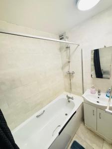 a white bathroom with a tub and a sink at The Bethnal Green Stay in London