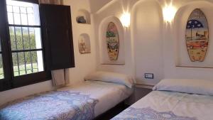 two beds in a room with windows and surfboards on the wall at Acacies 25 in Torroella de Montgrí
