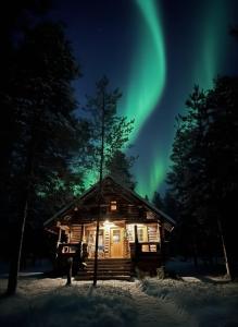 una cabaña de madera con las luces del norte en el cielo en Villa Kelotupa, en Hossa