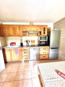 eine Küche mit Holzschränken und einem Edelstahlkühlschrank in der Unterkunft Nid douillet au pied des pistes in Les Angles