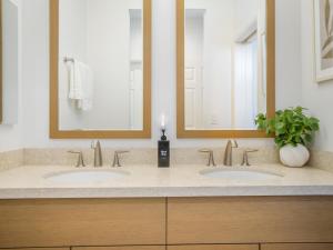 two sinks in a bathroom with two mirrors at Kalo Homes - Makaha Modern in Makaha Valley +62 photos