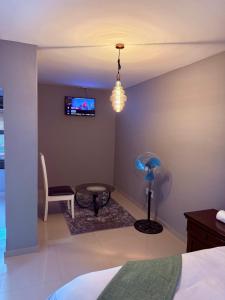 a bedroom with a bed and a tv and a chair at Ella Guest House in Pretoria