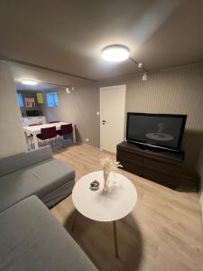 Una sala de estar con un sofá, una mesa y un televisor. en Modern basement apartment, en Stavanger