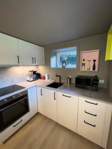 Una cocina con gabinetes blancos y un fregadero. en Modern basement apartment, en Stavanger