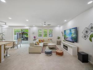 a living room with a couch and a tv on a wall at Kalo Homes - Elevated Escape in Makaha Valley