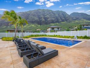 a swimming pool with lounge chairs and a mountain at Kalo Homes - Elevated Escape in Makaha Valley