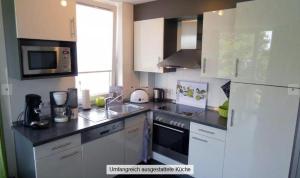 a kitchen with white cabinets and a counter top at Strandpark-Grossenbrode-Haus-Meeresrauschen-Wohnung-11 in Großenbrode-Kai +8 photos