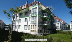 a large white building with a green stripe on it at Strandpark-Grossenbrode-Haus-Meeresrauschen-Wohnung-11 in Großenbrode-Kai