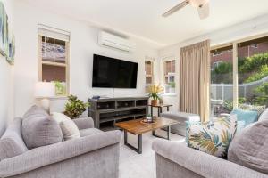 a living room with two couches and a flat screen tv at Kalo Homes Tropical Palm Getaway in Makaha Valley