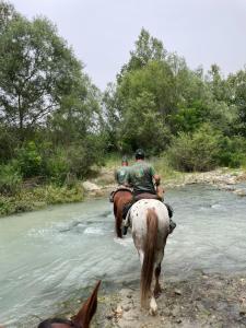 a group of people riding horses through a river at La Dimora di Armida in Torricella Peligna