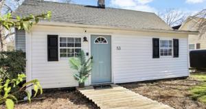 a small white house with a blue door at Mins to Downtown, Hospital, Airport in Greenville