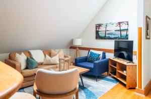 un soggiorno con un divano e una TV di South Swell Tofino (formerly Blue Heron Waterfront Home amid Old Growth Cedars) a Tofino