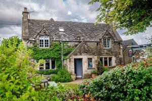 a large stone house with ivy on it at The Ragged Cot in Minchinhampton